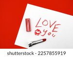 Love text with red lipstick kiss on white background with kiss. The inscription LOVE written in lipstick on a white background, top view. The concept of Valentine's Day February 14