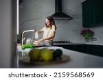 A young woman stands in the kitchen and cooks food with an electric mixer