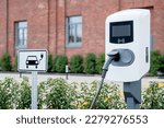 e-car charging station, e-car charge point or electric vehicle supply equipment (EVSE) with information sign electric car public charging point station and charge cable, charging plug parking spaces