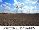 A lot of high-voltage power line, transmission tower overhead line masts, high voltage pylons as power pylons on the fields