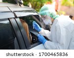 Doctor or nurse wearing PPE, N95 mask, face shield  and personal protective gown standing beside the car/road screening for Covid-19 virus, Nasal swab Test. 