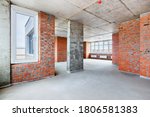 Small photo of A penthouse apartment room with the bare brick walls in new residential building under construction. The interior of an unfinished big flat without finishing.