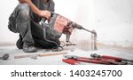Small photo of Installer stabs hole with Hilti rotary hammer in the wall on the construction site