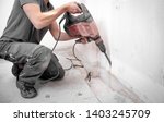 Small photo of Installer stabs hole with Hilti rotary hammer in the wall on the construction site
