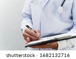 Cropped image of progress note on clipboard in doctor's hands while he write the patient's condition.