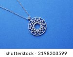 Small photo of Clone pendant in the shape of a circle with sparkling sterling silver cubic zirkonia on a chain. Beautiful jewelry for a woman. Jewelry decoration on a blue background.