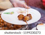 Small photo of DUBAI, UAE - APRIL 5, 2014: Three luqaimat doughnut balls on a plate being drizzled with dibs (date syrup). Luqaimat is a popular Arabian dessert that is often eaten during Ramadan.