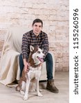 Small photo of A man and a hussy dog are posing in the studio. The basics of training pets.