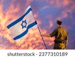 Small photo of Israeli soldier with Israel flag against a fiery sunset. Remembrance Day - Yom HaZikaron, Patriotic holiday, Israeli Independence Day - Yom Ha'atzmaut concept.