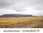Dried autumn steppe with a range of hills under thunderclouds. Kurai steppe, Altai, Siberia, Russia.