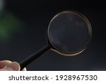 hand holding magnifying glass in dark room. concept of uncovering mystery, detective investigation, solve secret