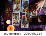 Small photo of Close-up of a fortune teller reading tarot cards on a table with purple tablecloth