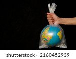 Small photo of Earth wrapped up in plastic bag. Globe in a plastic bag. Concept of plastic pollution of the earth. World Environment Day concept. Copy space. Save Earth Concept on black background Selective focus