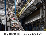 Conveyor belt transports garbage inside drum filter or rotating cylindrical sieve with trommel or sorting pieces of garbage into various sizes fractions at recycling plant