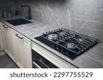 Small photo of Contemporary black tempered glass gas stove hob with four burners with auto ignition knob cast iron pan supports fan hood and square black sink built in compact high pressure laminate HPL countertop.