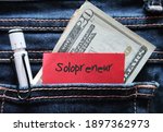 Pen , cash dollars money , red note in jeans pocket written SOLOPRENEUR ,a  person who sets up and runs business on their own