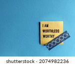 Note stick on copy space blue background with text I AM WORTHLESS change to I AM WORTHY, concept of self talk affirmation to overcome low self esteem, to love and accept value of oneself