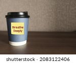 Small photo of Coffee cup on copy space background with text note written Breathe Deeply, concept of self reminder to calm down and lower stress in the body, inhale exhale deeply and concentrate to