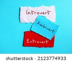 Torn paper on blue background with handwritten text - INTROVERT EXTROVERT AMBIVERT, Introvert tend to feel drained after socializing, extrovert tend to feel energized, ambivert in the middle