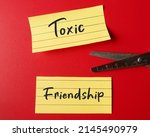 Small photo of Scissors cutting note paper with handwritten TOXIC FRIENDSHIP, refers to friends who leave negative effects - mentally energy drain and bring down emotionally