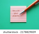 Small photo of Note pad on green background with handwritten text YOU ARE YOUR PRIORITY, concept of stop being people pleaser and ignore our own needs,boost self love and prioritising self care