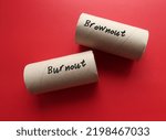 Small photo of Toilet paper roll on red background with handwritten text BROWNOUT and BURNOUT, concept of brownout syndrome which workers feel overworked, demotivated and disengaged – stage before burnout