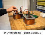 Small photo of Repetitive movement of the magnet by hand will induce the second magnet on a spring to start vibrating. Physics induction experiment. Selective focus.