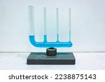 Small photo of Glass equipment where several different connected tubes are filled with a blue liquid, demonstrating capillary action. Used in physics class.