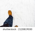 top view of yellow leather boot on snow-covered path on overcast winter day