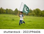 cheerful active little boy running and waving Pakistani flag, celebrating Pakistan Independence day.