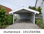 Small photo of Carport with pitched roof, white wood with opeln driveway on pebble floor next to a house. Germany, Europe