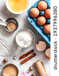 Small photo of Baking ingredients and kitchen utensils on a white background top view. Baking background. Flour, eggs, sugar, spices, and a whisk on the kitchen table. Flat lay.