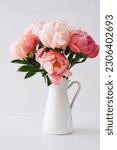 Small photo of Beautiful bouquet of fresh coral peony flowers in full bloom in vase. Floral still life with blooming peonies.