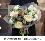 Magnificent rustic bouquet of tulips, roses and other flowers and herbs. Young woman holding rustic beautiful bouquet of interesting flowers.