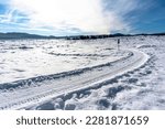 Snowy road with blue sky in the background the peaks of the mountains of the Asiago plateau and the woods of the Piana di Marcesina with small alpine huts in Marcesina Enego Vicenza Veneto Italy
