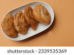 Small photo of deep fried curry puff,curry puff pastry, karipap,epok epok, spiral curry puff isolated a orange pastel backdrop . thai curry puff concept.this pastry is asian traditional snacks