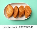Small photo of deep fried curry puff,curry puff pastry, karipap,epok epok, spiral curry puff isolated a green pastel backdrop . thai curry puff concept.this pastry is asian traditional snacks
