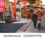 Small photo of Kyoto, Japan - Circa 2016: Bald boy with his son by the hand walking through small shrines with torii gate at the shrine at Fushimi Inari taisha shrine
