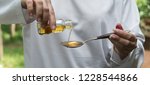 Small photo of pouring medication or antipathetic syrup from bottle to spoon, healthcare