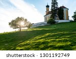 Small photo of bavarian church on an hill with an outshined tree seen from a low point of view