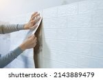 Small photo of Worker hands sticking wallpaper on wall, Home decoration by yourself, Copy space.