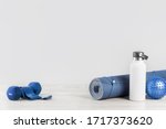 Rolled blue yoga mat and white metal water bottle flask grey