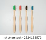Small photo of Bamboo toothbrushes in different colors. Wooden toothbrush on a white background. Toothbrush close-up.