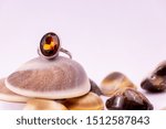 Small photo of Gemstone ring gift concept. A cinnamon stone ring on seashell on white background