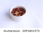 Small photo of A healthy breakfast is herculean porridge with the addition of nuts and dried fruits in a white bowl, isolated on a white background. Side view. Healthy food, carbohydrates. Side view.