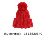 Small red knitted bobble hat isolated on a white background. Handmade woolly hat with pompom. Closeup. Copy space