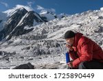 High altitude sickness. Climber breathing oxygen from the O2 tank on the background of glacier and covered with snow and ice mountains.