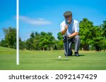 Small photo of Asian senior man holding golf club hitting golf ball on fairway at country club in sunny day. Healthy elderly male golfer enjoy outdoor activity sport golfing at golf course on summer vacation