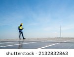 Small photo of African man engineer using digital tablet maintaining solar cell panels on building rooftop. Technician working outdoor on ecological solar farm construction. Renewable clean energy technology concept