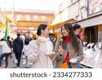 Asian woman friends eating street food sweet egg roll together while travel at fish market in Tokyo city, Japan. Attractive girl enjoy and fun outdoor lifestyle travel street market on autumn vacation